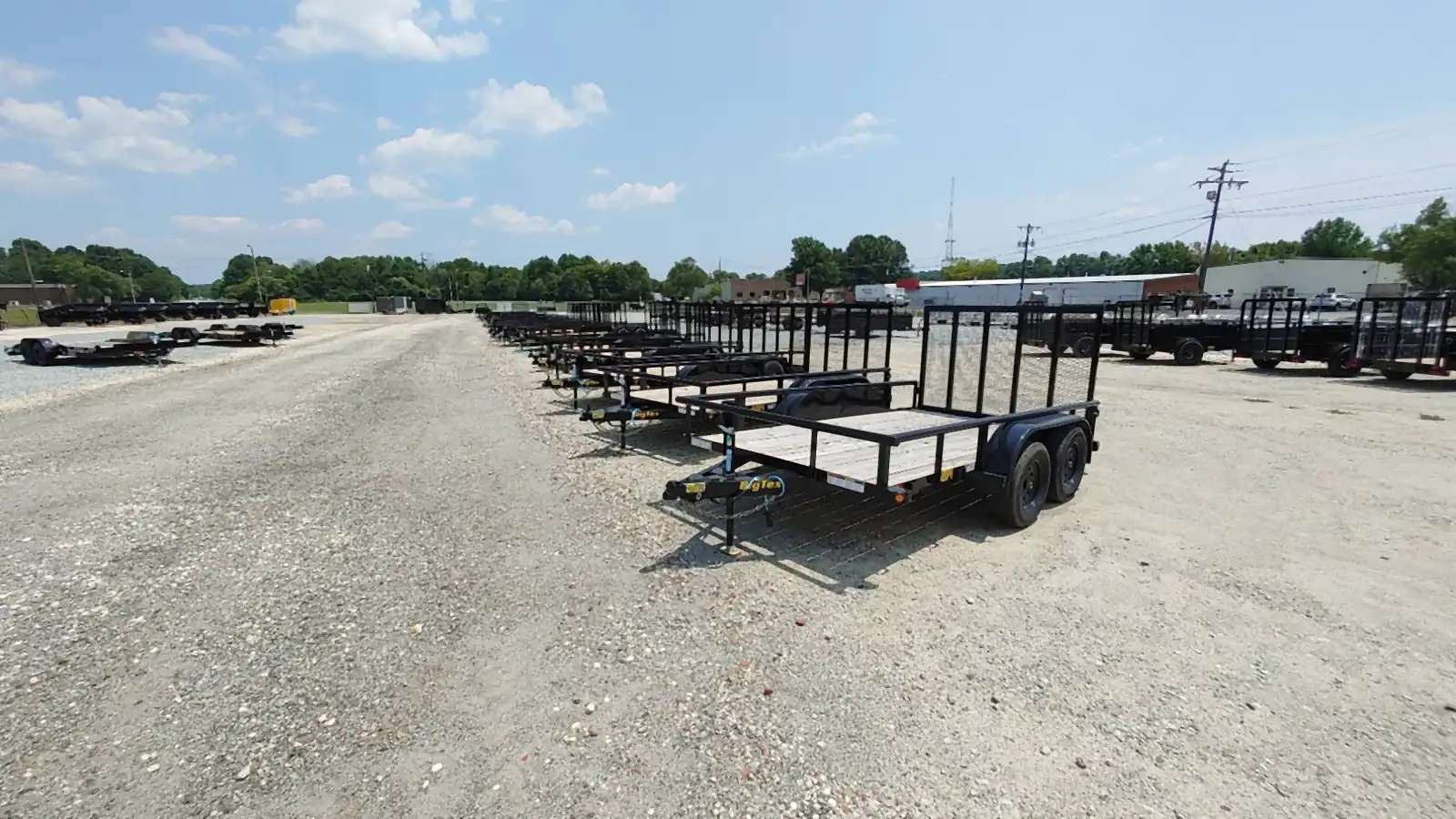 Row of utility trailers on a gravel sales lot